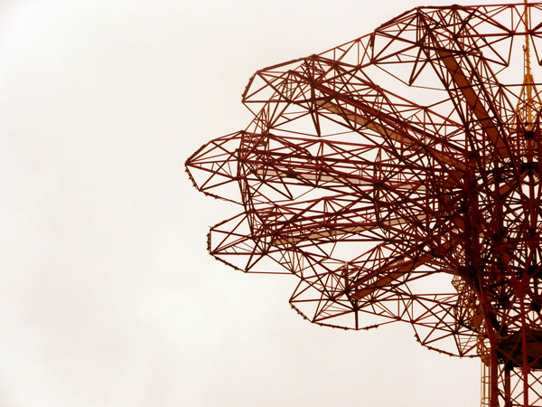 A tower, made of a network of steel beams, stands
against the sky.