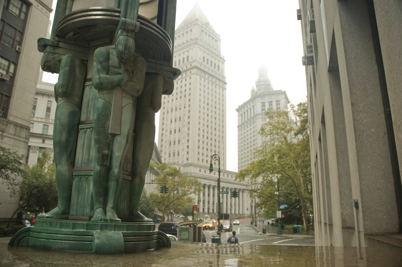 Statuettes of wrestlers decorate an entrance, with municipal buildings in the distance.