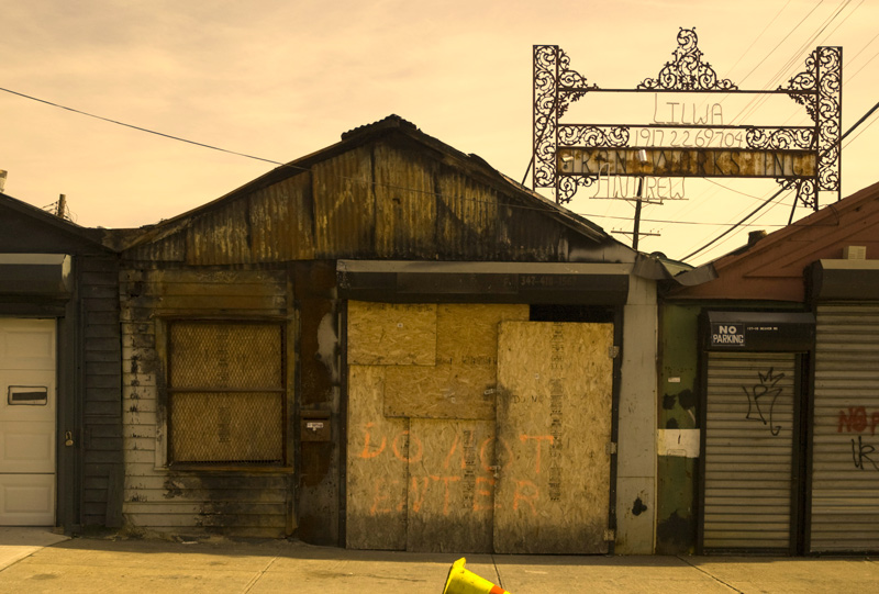 An ornate metal sign hangs over a metal worker's shop.