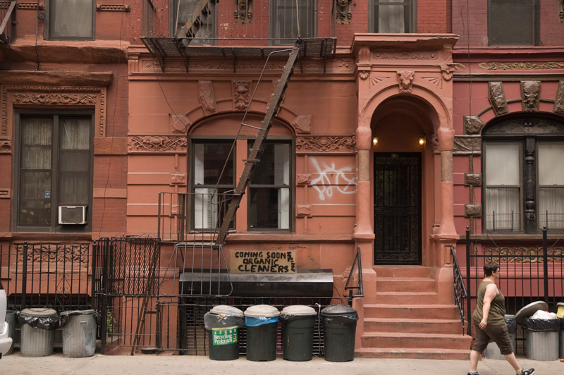 A woman walks past a row of old tenement houses.