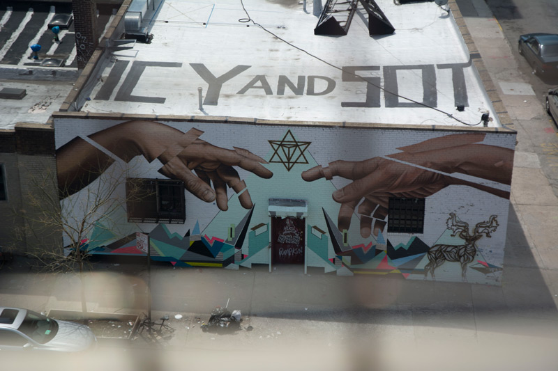 A building with a mural based on the Sistine Chapeil has 'Ice and Sot' painted on its roof.