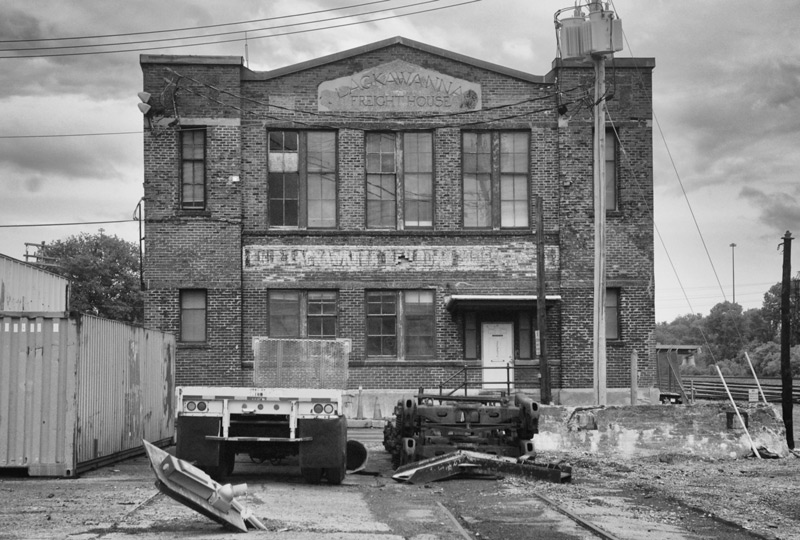 An old brick railroad building, with heavy equipment out front.
