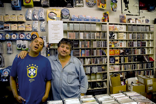 Two colleagues pose in front of inventory.